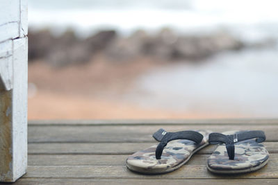 Close-up of shoes on pier against sea