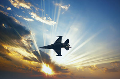 Low angle view of airplane flying against sky during sunset