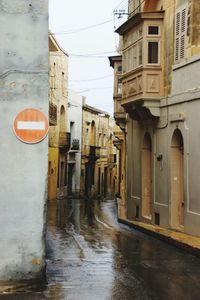 Wet street amidst buildings during rainy season