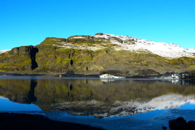 Scenic view of sea and mountains against clear blue sky