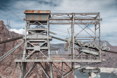 Ski lift station by rocky mountains against sky