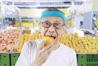 Portrait of senior man eating apple in supermarket