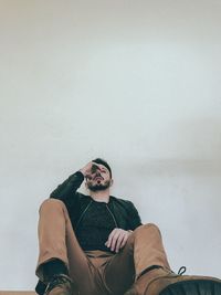 Low angle view of man sitting against wall
