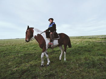 Man riding horse standing on field