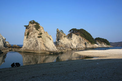 Rocks on beach against clear blue sky