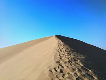 Scenic view of desert against clear blue sky