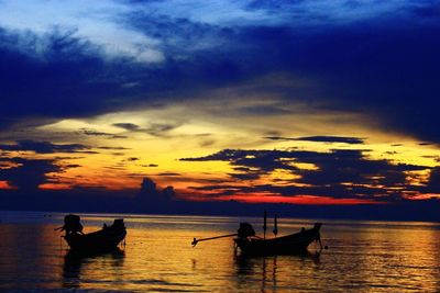 Silhouette people on sea against sky during sunset