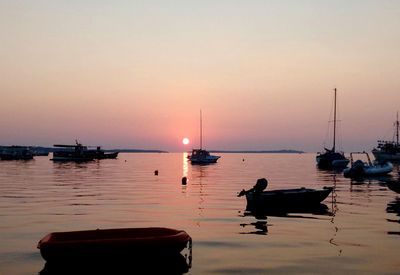 Silhouette sailboats moored on sea against sky during sunset