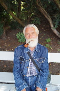 Portrait of bearded mature man smoking while sitting on bench