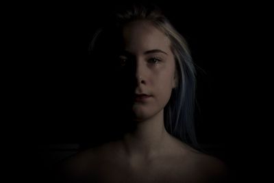 Portrait of beautiful young woman over black background
