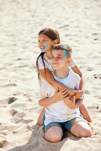 Cute sibling embracing while sitting on beach