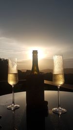 Close-up of wine glass on table against sky during sunset