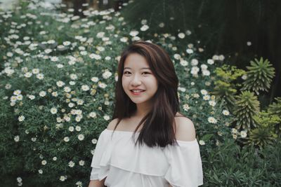 Portrait of smiling young woman standing by tree