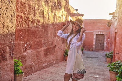 Young woman standing against wall