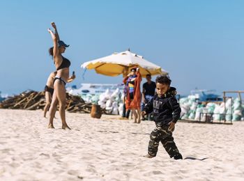 People at beach against clear sky