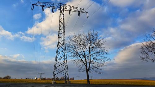 Low angle view of electricity pylon on field against sky