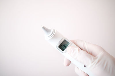 Close-up of hand holding camera over white background