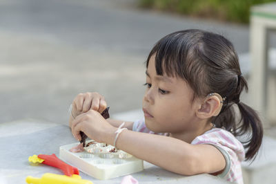 Close-up of cute girl playing with childs play clay at table outdoors