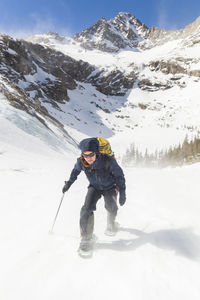 Hiker battles wind above black lake, rocky mountain national park