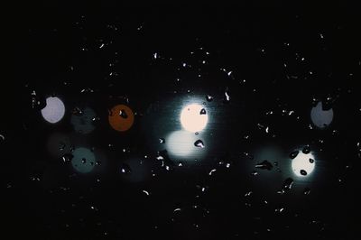 Close-up of water drops on black against sky at night