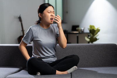 Young woman using mobile phone while sitting at home