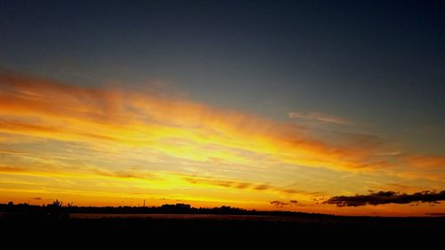 Scenic view of dramatic sky over silhouette landscape during sunset