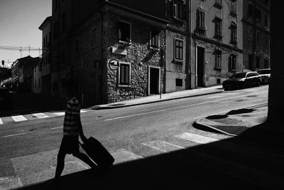 Shadow of person on street amidst buildings in city
