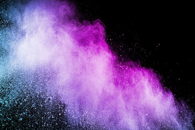 Defocused image of multi colored powder paints against black background