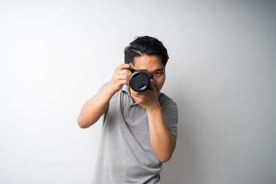 Midsection of man photographing against white background