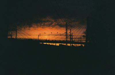 Silhouette electricity pylon against sky during sunset