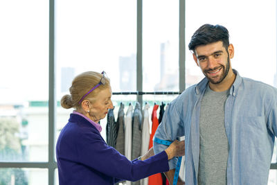 Portrait of smiling young man standing against window