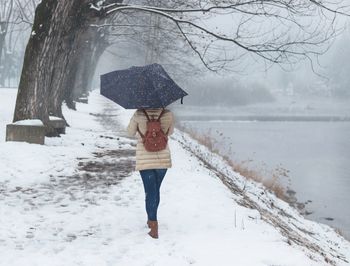 Full length of young woman walking on snow covered landscape