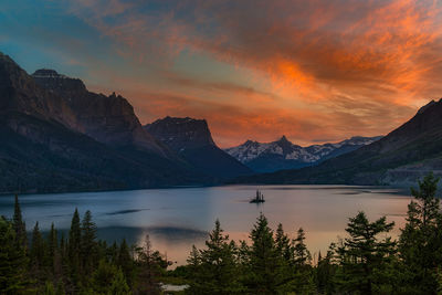 Scenic view of lake by mountains against sky during sunset