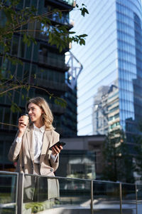 Portrait of young woman standing against buildings