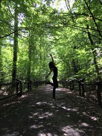 Full length of woman standing on street amidst trees in forest