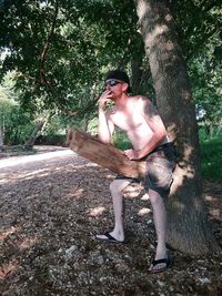 Full length of shirtless man in forest