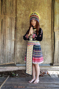 Portrait of woman wearing traditional clothing standing against wall