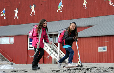 Full length of a smiling girl standing against building