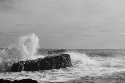 Waves splashing on sea against sky