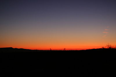 Silhouette landscape against clear sky during sunset