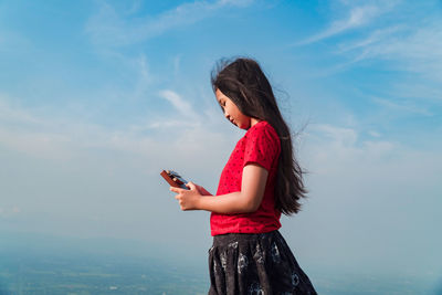 Woman using mobile phone against sky