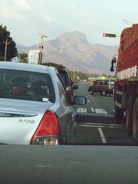 Vehicles on road against mountains in city