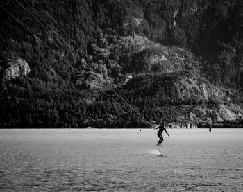 Man kiteboarding on sea against mountains