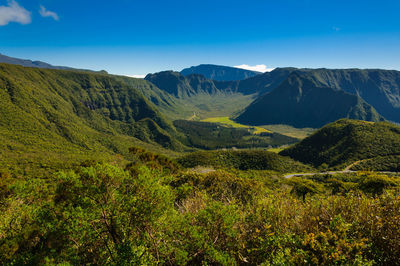 Scenic view of landscape and mountains against blue sky