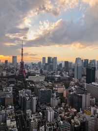 Aerial view of buildings in city against cloudy sky