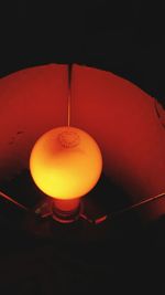 Close-up of illuminated lamp hanging against black background