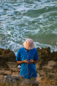 Portrait of young adult standing at beach using mobile phone