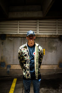 Portrait of young man standing against wall