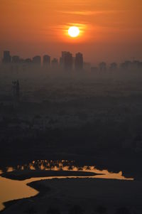 Scenic view of silhouette cityscape against sky during sunset