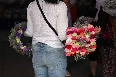 Midsection of florist carrying flower wreath decorations